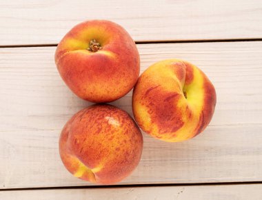 Tahta bir masada üç sulu olgun şeftali, yakın plan, üst manzara..