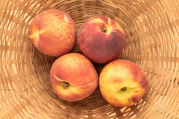 Kamış kasesinde bir kaç sulu olgun şeftali, yakın plan, üst manzara..