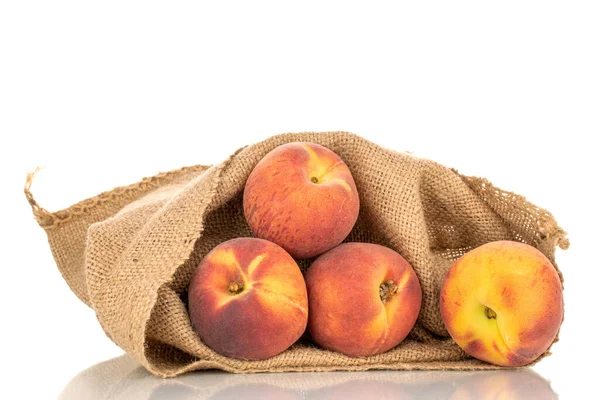 Birkaç tatlı organik şeftali, jüt çantalı, yakın plan, beyaz arka planda izole edilmiş..