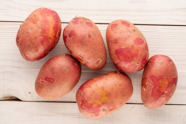 Tahta bir masanın üzerinde birkaç organik pembe patates, yakın plan, üst manzara..