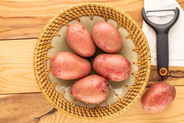 Tahta bir masanın üzerinde seramik tabakla birkaç organik pembe patates, yakın plan, üst manzara..