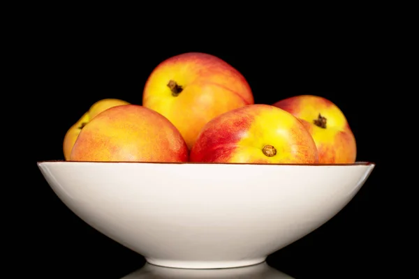 Seramik bir tabakta birkaç tatlı organik nektarin, siyah bir arka planda izole edilmiş yakın plan..