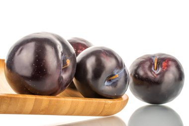 Bambu kabında çeşitli organik ve lezzetli mor erikler, yakın plan, beyaz üzerine izole edilmiş..