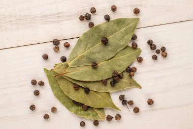 Kuru kokulu karabiber ve defne yaprağı ahşap bir masada, yakın plan, üst manzara.