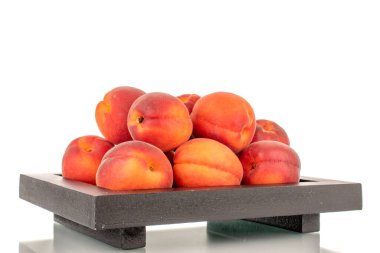 Tahta tepside birkaç tane olgun kırmızı kayısı, yakın plan, beyaz arka planda izole edilmiş..