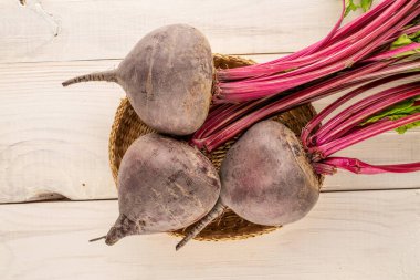 Üç tatlı kırmızı pancar bir saman tabağında ahşap bir masada, yakın plan, üst manzara.