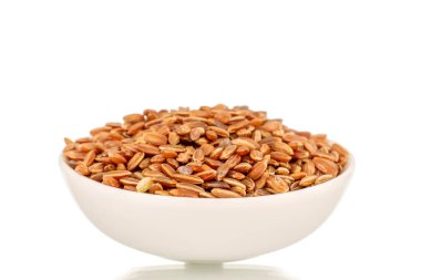 Beyaz seramik tabakta pişmemiş organik kahverengi pirinç, yakın plan, beyaz arka planda izole edilmiş..