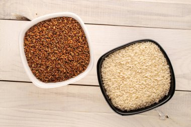 Organik pişmemiş beyaz ve kahverengi pirinç, seramik tabaklarda, ahşap bir masada, yakın plan, üst manzara..