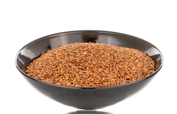 Siyah seramik tabakta pişmemiş organik kahverengi pirinç, yakın plan, beyaz arka planda izole edilmiş..