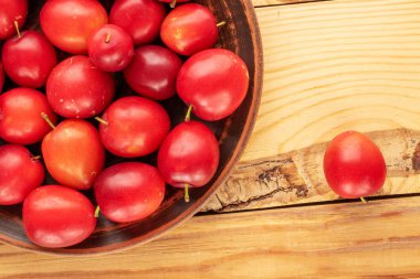Ahşap bir masada, yakın planda, üstten görünüşlü, kirazlı birkaç tatlı erik..