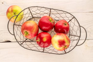 Tahta bir masada sepetin içinde birkaç sulu kırmızı elma, makro, üst manzara..