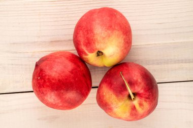 Tahta bir masada üç tatlı nektarin, makro, üst manzara..