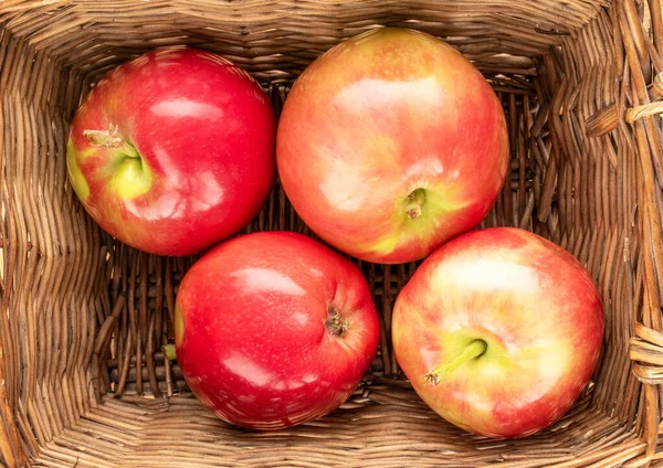 Four juicy red apples in a vine basket, macro, top view.