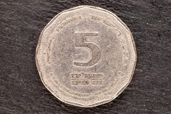 One Israeli metal coin on a slate stone, close-up, top view.