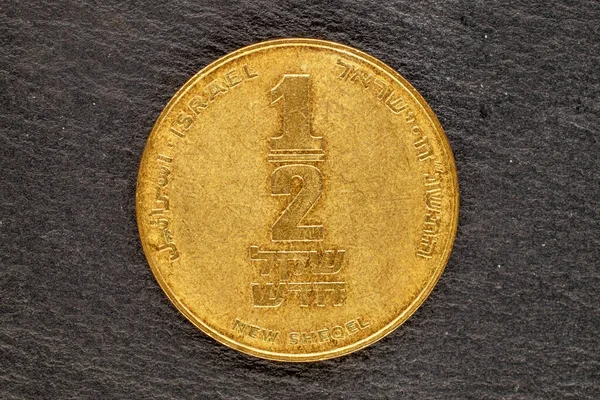 One Israeli metal coin on a slate stone, close-up, top view.