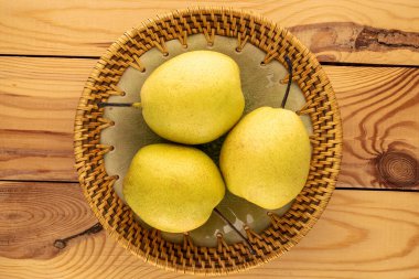 Tahta bir masada seramik bir tabakta üç tatlı parlak armut, yakın plan, üst manzara..