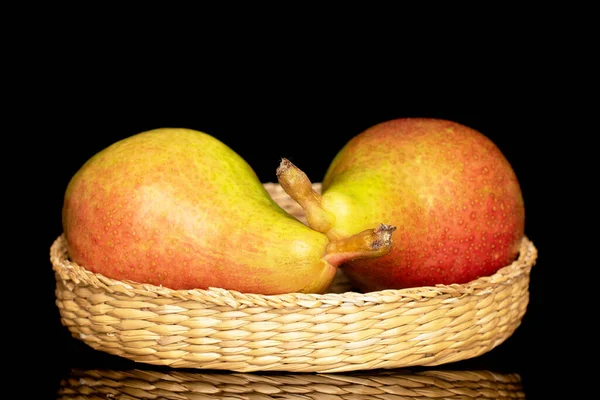 Two juicy pears on a straw plate, close-up, isolated on a black background.