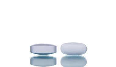 Two medical tablets, macro, isolated on a white background.