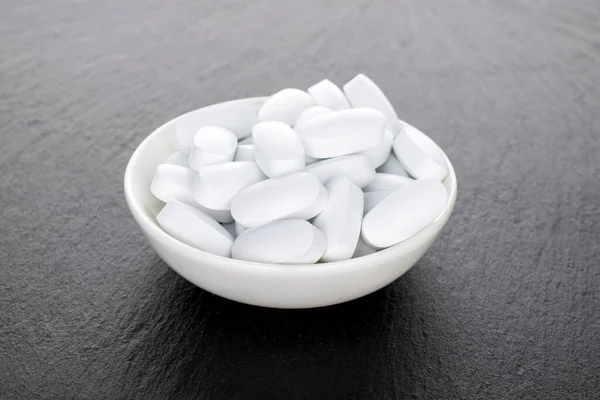 Several Vitamin Tablets White Ceramic Saucer Close Slate Stone — Zdjęcie stockowe