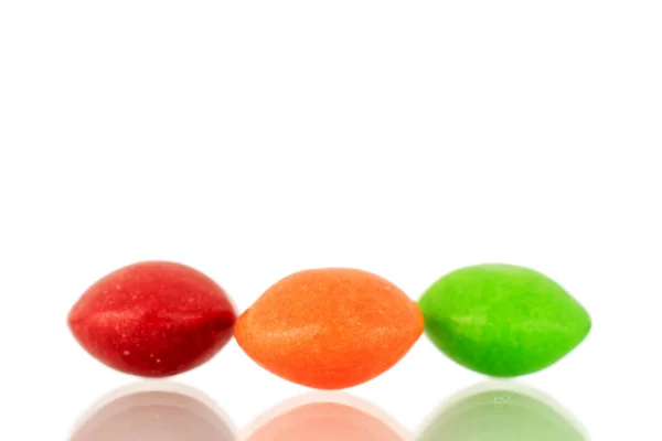 Three sweet colored candies, close-up, isolated on a white background.
