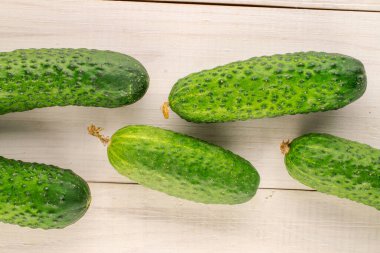 Several ripe green cucumbers on a wooden table, close-up, top view.