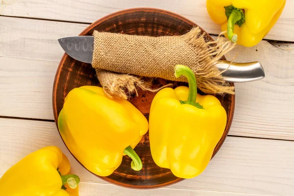 Four Ripe Yellow Sweet Peppers Clay Plate Knife Wooden Table — Stockfoto