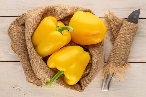 Three Ripe Yellow Sweet Peppers Jute Bag Knife Wooden Table — Stockfoto