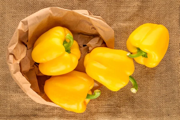 Four Ripe Yellow Sweet Peppers Paper Bag Jute Fabric Close — Stockfoto