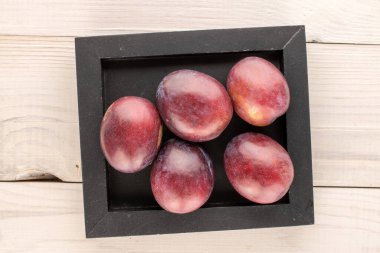 Ahşap bir masa üzerinde ahşap bir tepsi ile birkaç tatlı erik, makro, üst görünüm.