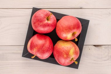 Ahşap bir masa üzerinde ahşap tepsi ile birkaç tatlı kırmızı elma, makro, üst manzara.