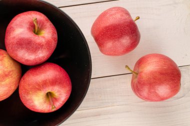 Tahta bir masanın üzerinde seramik siyah plakalı birkaç tatlı kırmızı elma, makro, üst manzara..