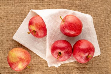 Beyaz keten peçeteli birkaç tatlı kırmızı elma jüt kumaş, makro, üst manzara.