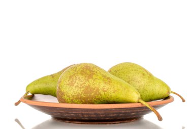 Beyaz arka planda izole edilmiş, makro killi bir tabakta üç sulu organik armut..