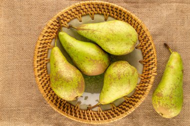 Jüt kumaş, makro, üst manzara üzerinde seramik bir tabakta birkaç sulu armut..