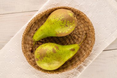 İki sulu armut, ahşap bir masada saman tabağı, makro, üst manzara..