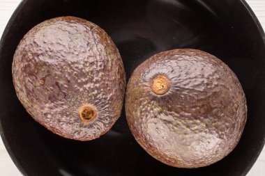 Siyah seramik tabakta iki olgun avokado, makro, üst manzara..