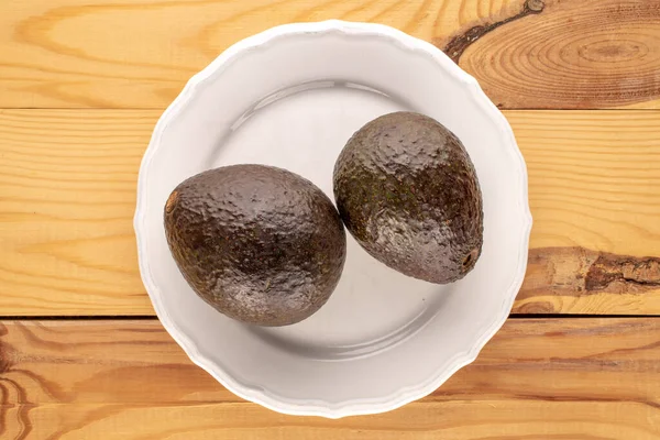 Two Ripe Avocados White Ceramic Plate Wooden Table Macro Top — Stock Photo, Image