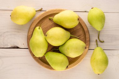 Ahşap bir masanın üzerinde, ahşap bir tabakta birkaç tatlı armut, makro, üst manzara..