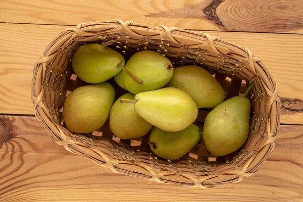 Several sweet pears in a basket on a wooden table, macro, top view.