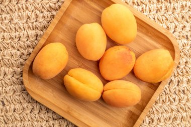 Bambu bir tabakta birkaç sulu sarı ananas kayısı, yakın plan, bir hasır paspas, üst görüş..