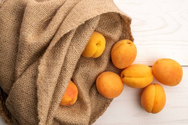 Birkaç organik sarı ananas kayısı jüt bir çantada, yakın planda, beyaz ahşap bir masada, üst tarafta..