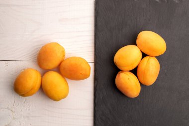 Birkaç olgun sarı ananas kayısı, yakın plan, tahta üzerinde ve beyaz ahşap masa, üst görüş..