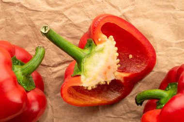 Bir buçuk ve iki kırmızı dolma biber, yakın plan, el işi kağıt üzerinde, üst manzara..