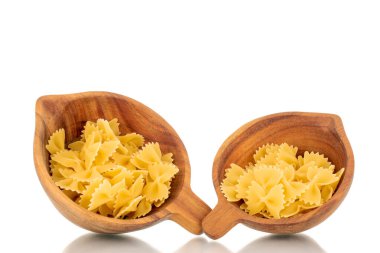 İki tahta fincanda birkaç çiğ kelebek makarna, makro, beyaz arka planda izole edilmiş..