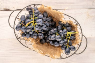 Tahta masadaki sepetin içinde bir dal siyah üzüm, makro, üst manzara..