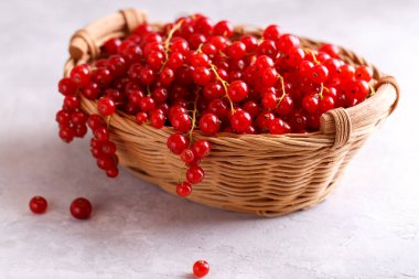 Gri taşlı arka planda sepette olgun kırmızı üzümler