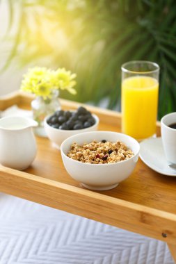 Tahta tepside kahvaltı, otel odasında yatak, romantik bir sabah ve sağlıklı yiyecekler. 