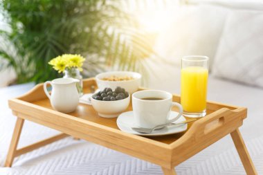 Tahta tepside kahvaltı, otel odasında yatak, romantik bir sabah ve sağlıklı yiyecekler. 