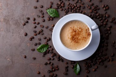Cup of coffee cappuccino and coffee beans on the brown stone background 