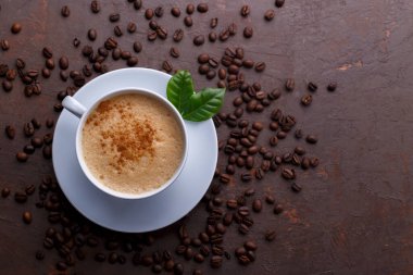 Cup of coffee cappuccino and coffee beans on the brown stone background 